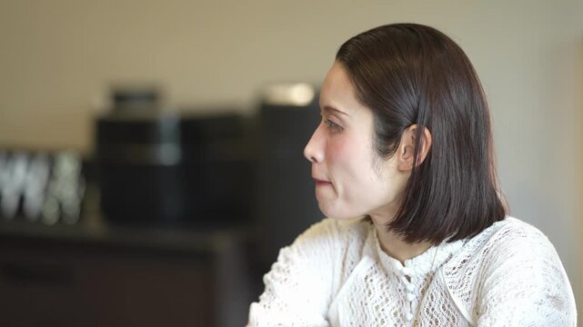 Woman gazes thoughtfully, quiet, reflective mood. Soft light highlights her calm, contemplative expression. Cozy interior suggests peaceful pause or quiet decision. Ideal for tranquil, introspective