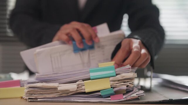 Office Employee Categorizing Business Documents with Color-Coded Tabs for Efficient Records Management