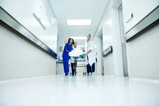 Surgery, accident and team with doctors in hospital for space, medical crisis and emergency. Healthcare, injury and operation with people and patient in clinic for corridor, help and low angle