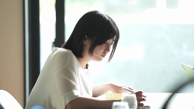 Soft light glows through window behind her. She writes quietly, focused, thoughtful. Her short hair frames her calm expression. Perfect for quiet study, work, or creative moments