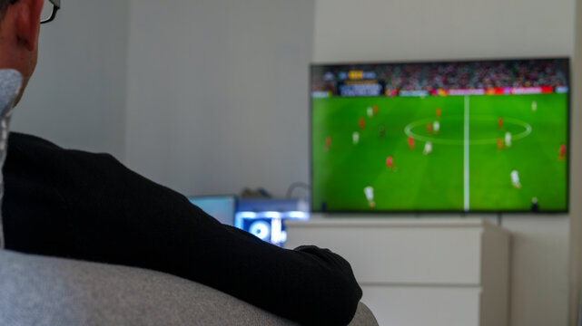 Person watching football match on television at home