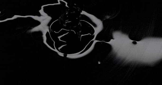 Black viscous liquid fast spiral. Close-up of thick black fluid flowing in rapid swirling spirals with white highlights.