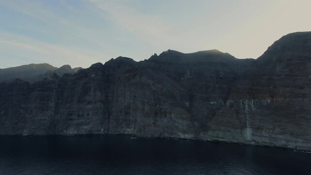 Majestic aerial drone shot revealing the impressive Los Gigantes cliffs plunging into the Atlantic Ocean during a beautiful sunset in Tenerife