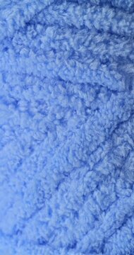 Blue fluffy yarn texture. Close-up soft chenille fabric with braided fluffy surface, smooth motion. Ideal for fashion, cozy and textile backgrounds. 