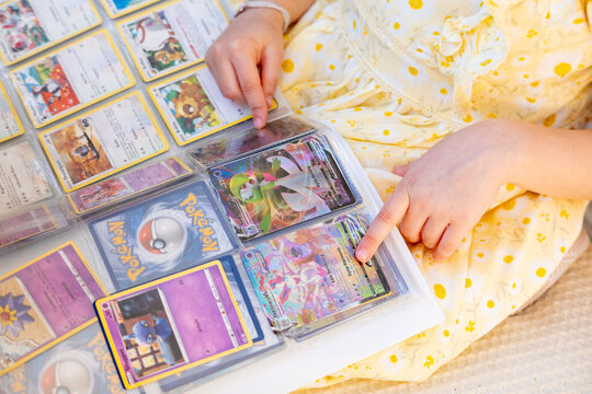 Young enthusiast child collecting Pokemon Trading Cards, album collectible hobby, German language Educational Games, playful Pokemon Fan Culture influence on kids, Childhood imagination and play