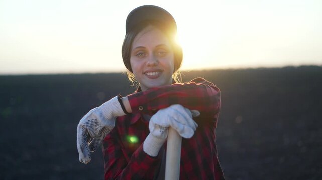 Farmer portrait with shovel silhouette in field. Confident woman farmer holding shovel at sunset. Rural lifestyle in agriculture. Determined farmer portrait with shovel, field silhouette at sunset.