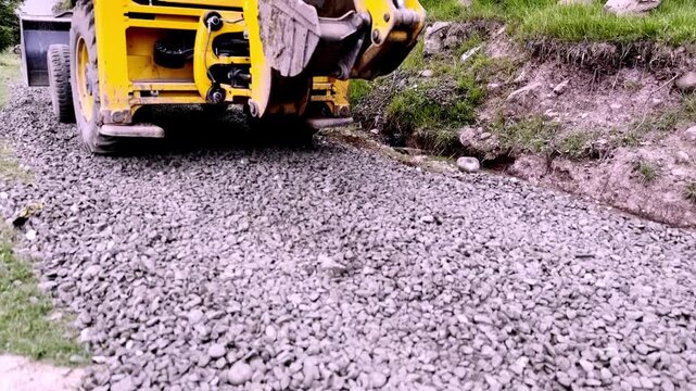JCB Machine Leveling Gravel on Road Construction Site for Highway Infrastructure Development, Civil Engineering and Earthmoving Equipment Operations Progress