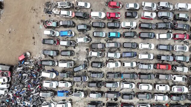 Aerial view of a densely packed car junkyard with rows of dismantled vehicles, showcasing various colors and models, highlighting the extensive collection of auto parts and scrap materials