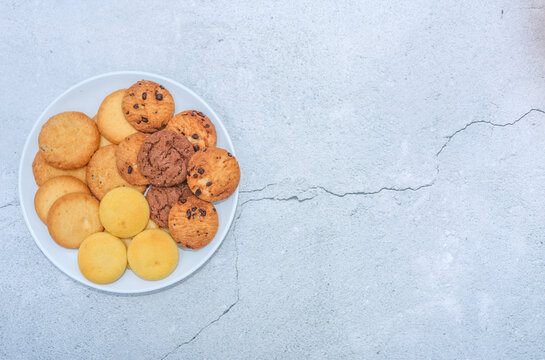 Assorted cookies and biscuits on a plate on the table. Collection of sweet baked snacks including chocolate cookies, butter biscuits, crackers and sandwich cookies on a plate