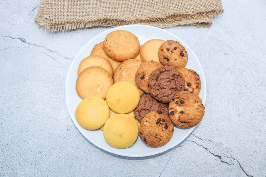 Assorted cookies and biscuits on a plate on the table. Collection of sweet baked snacks including chocolate cookies, butter biscuits, crackers and sandwich cookies on a plate