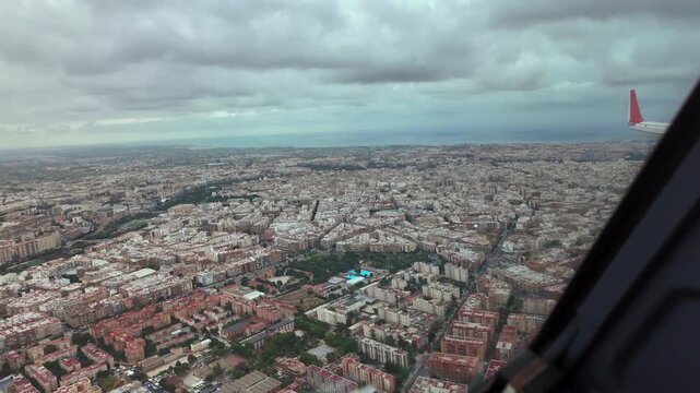 Right side cockpit window view of Valencia city center captured during the final approach whilke overflying the city with a clouded sky.
