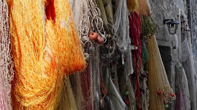 Colorful fishing nets hanging on a stone wall in the isola dei pescatori, one of the borromean islands on lake maggiore, italy