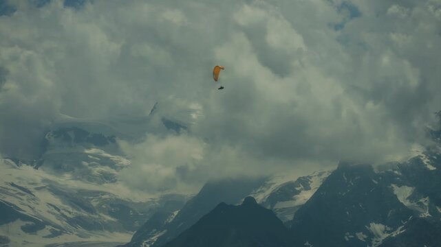 Wide shot of paraglider flying above mountains in the alps in summer.