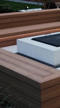 Vertical video. Wooden terrace with porch and LED lighting beside a modern house. Cozy outdoor patio.
