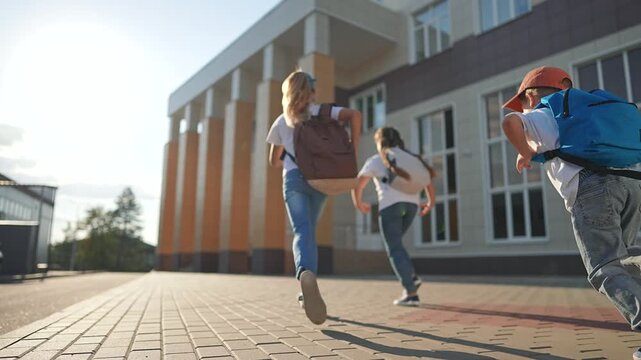 Pupils walking school with backpacks. Excited children first school day. Back to school scene with pupils carrying backpacks. First day at school for pupils. Children with backpacks heading building.