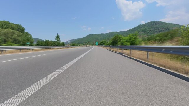 Car POV driving on a scenic highway through mountains on sunny day