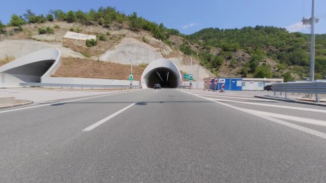 Car POV approaching and entering a modern highway road tunnel
