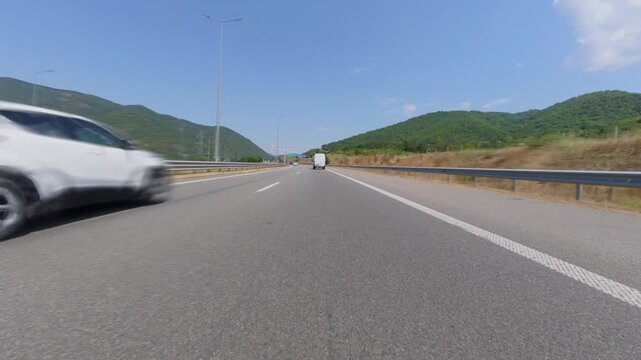 Car POV driving on a scenic highway through mountains on sunny day