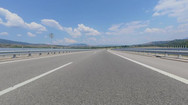 Car POV driving on a scenic highway through mountains on sunny day