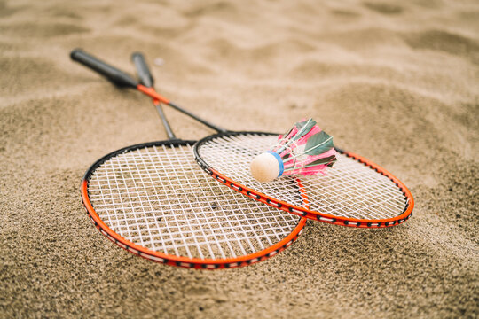 Badminton Shuttlecock and Racket on Sandy Beach. pink shuttlecocks and rackets on a summer day. The concept of outdoor sports games