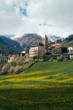 Alpine mountain scenery with blooming meadows and village of Ramosch in spring, Valsot, Engadin Valley, Switzerland