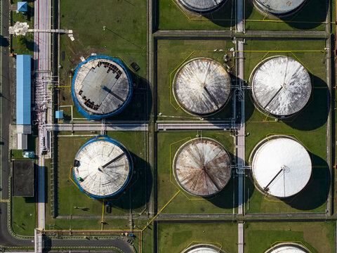 Aerial view of the Fuel Oil Terminal featuring large circular storage tanks, industrial piping, and surrounding green grounds in Manggis, Bali, Indonesia.