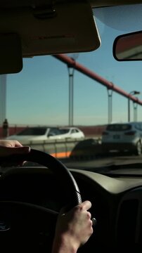 Vertical video: Driving driver holding steering wheel while entering red bridge, maintaining lane