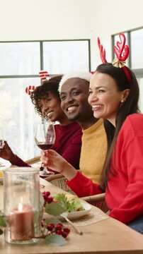 Vertical video: Toasting after cue 3 friends wearing hats with wine glasses at table celebrating