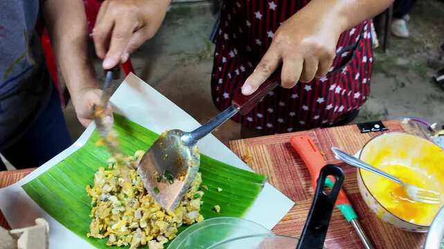 Freshly cooked Thai street food served on a green banana leaf before wrapping for takeaway at a local night market in Thailand. Authentic traditional food presentation captured in 4K.