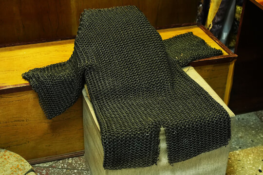 Medieval chainmail armor laid on an old wooden chest in a historical museum or workshop. Iron protection gear.