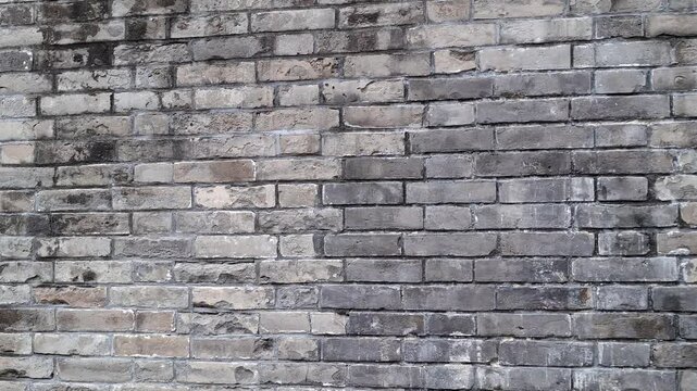 Detailed texture of old weathered gray brick wall. Rustic stone patterns, uneven brickwork blocks, rough masonry details and vintage architectural. Industrial and loft design. Grungy grey background