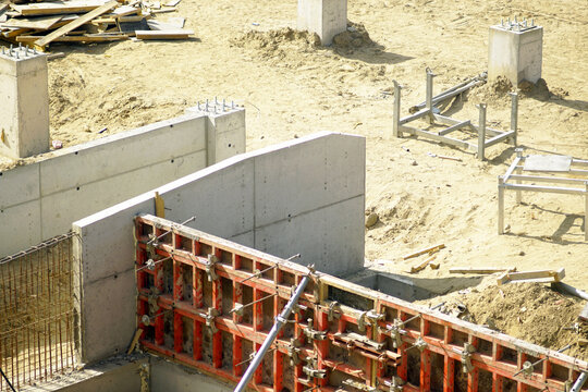 Concrete foundation walls with modular formwork installed on active building site. Highlights reusable forming systems, scalable construction workflows, and reinforced infrastructure delivery.