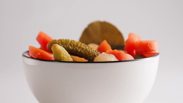 Close-up of assorted pickled vegetables served in a deep bowl. Traditional appetizer with cucumbers, carrots, olives and mixed preserved vegetables. High quality 4k footage