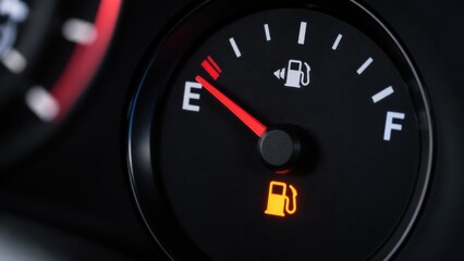 Fototapeta premium Illuminated fuel warning light on car dashboard indicates low tank levels with red needle pointing near empty marking for driver safety