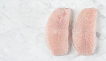 Fototapeta premium Two Raw Corvina Fillets on White Marble Surface