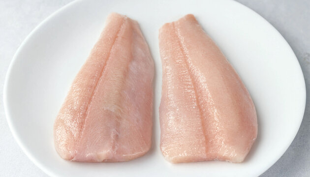 Two Raw Yellow Croaker Fillets on White Plate