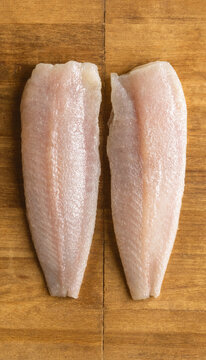Two Raw Yellow Croaker Fillets on Wooden Board