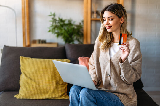 Smiling woman using credit card and laptop at home, representing fintech innovation, digital finance