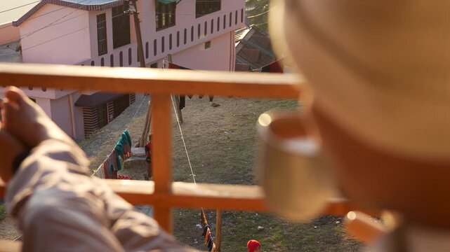 Relaxing on a balcony with a hot drink overlooking a mountain village in Chakrata, Dehradun, Uttarakhand