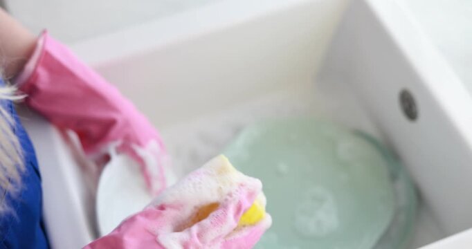 Teenage worker washing dishes near sink in kitchen, closeup. Part-time job