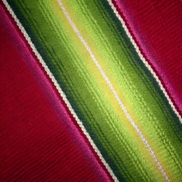 close up of magenta and green mexican sarape blanket fabric texture with striped pattern