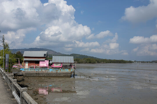 Colorful pink house boat near tropical island under cloudy blue sky