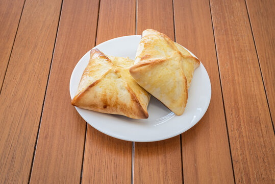 Two Brazilian esfirra served on plate over wood