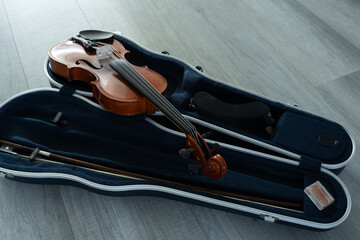 A violin rests on its open case lying on a light-colored floor, ready for practice or performance in a home studio. Music lesson advertisements, instrument storage inspiration, musician lifestyle © Ann