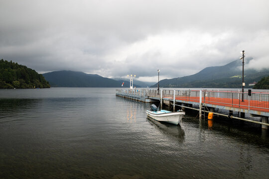 Tranquil view of Lake Ashi with pier and boat on an overcast day, Japan