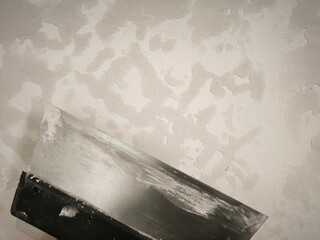 Fototapeta premium A metal spatula with putty residue on a wall background