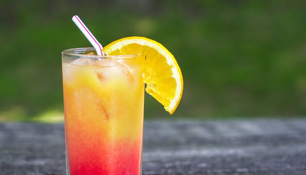 Tequila sunrise cocktail with orange slice and straw