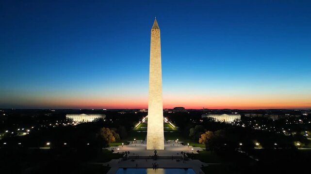 The tall stone obelisk stands against a colorful sunset sky