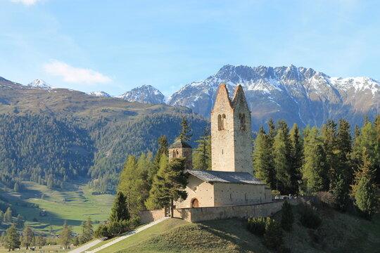 Historic San Gian Church on a hill in Celerina with snow-capped Swiss Alps mountains, Engadin