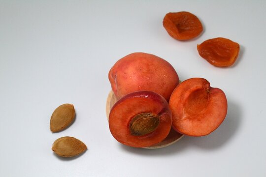 Fresh ripe apricots with apricot kernels and dried apricots arranged on white background with copy space. Healthy fruit comparison and natural food ingredient concept.
